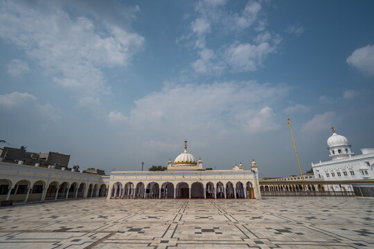 View of white marble architecture gleams under a vast blue sky, a serene ground photo capturing the spiritual essence of the sacred site, Nankana Sahib, Punjab, Pakistan.