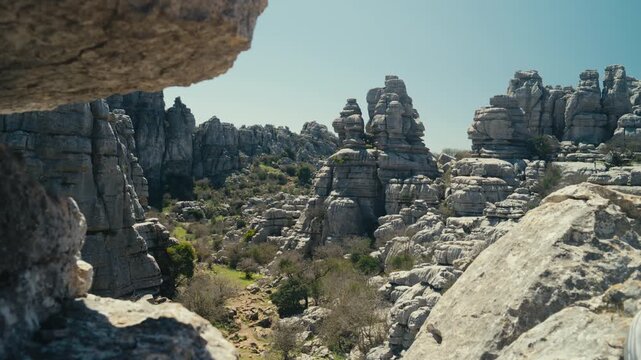 Scenic valley framed by limestone rock formations in El Torcal de Antequera, Spain, showcasing dramatic karst landscape, layered geology and natural textures in bright daylight.