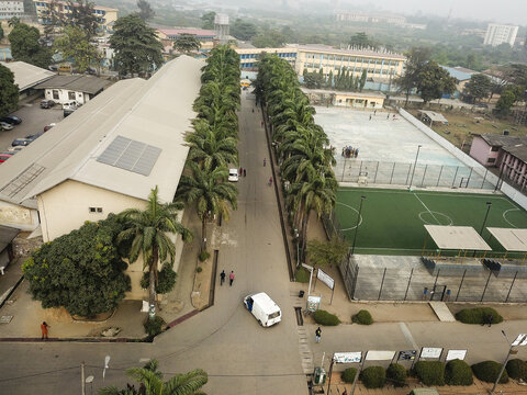 Aerial view of the road stretches through Akoka, flanked by buildings and a vibrant green sports field, Oworonshoki, Lagos, Nigeria.