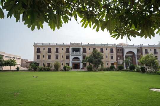 View of sprawling lush green lawn leading up to an elegant building with symmetrical archways, a glimpse of history in Nankana Sahib, Punjab, Pakistan.