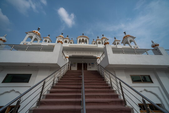 View of the striking white architecture of a Sikh temple rising majestically against a clear blue sky in Nankana Sahib, Punjab, Pakistan.