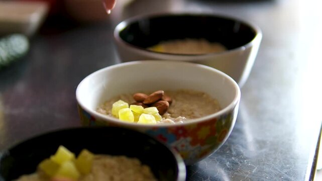 Oatmeal bowls with nuts dried fruits pineapple closeup healthy breakfast variety plates