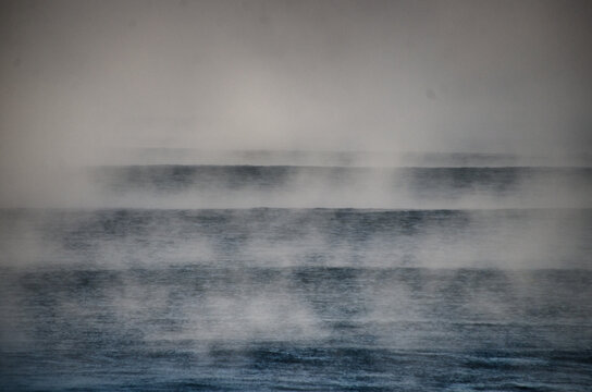 View of ethereal mist hangs low over the dark, mysterious waters, creating a sense of serene isolation and quiet drama, Hossegor, France.