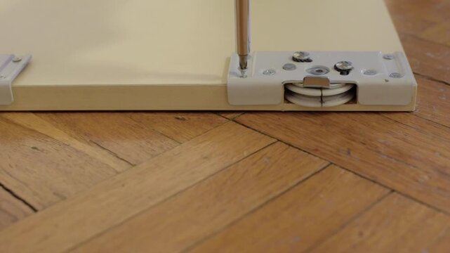 Wheel adjustment process. Adjusting wheel with screwdriver carefully. Screwdriver is used to align roller properly. Finetuning wheel position using screwdriver on door edge