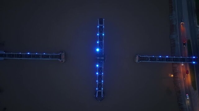 Aerial ascending overhead of a train trestle that is lit up at night located on the Cumberland River in Clarksville, TN