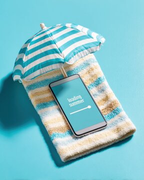 Smartphone with loading summer screen on striped beach towel under blue and white sun umbrella