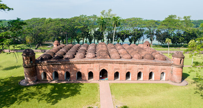 Aerial view of the Sixty Dome Mosque's red brick contrasting against the lush green lawn under the bright sky, Bagerhat, Khulna Division, Bangladesh.