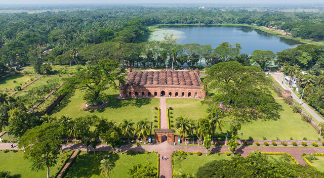 Aerial view of the Sixty Dome Mosque stands majestically amidst lush greenery, contrasting with the serene waters of a nearby lake, Bagerhat, Khulna Division, Bangladesh.
