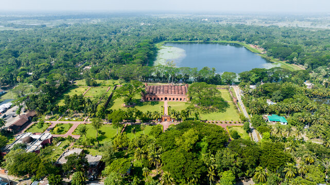 Aerial view of the Sixty Dome Mosque, a historical landmark with its intricate brickwork, stands amidst lush greenery and a serene lake, Bagerhat, Khulna Division, Bangladesh.