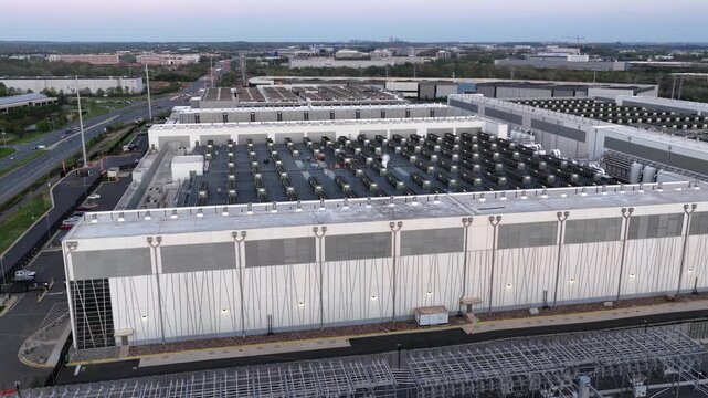 Aerial wide shot of large data center campus in Ashburn, Virginia, with rooftop cooling systems and surrounding roads. Modern AI infrastructure and digital economy in United States.