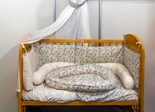 Empty wooden frame baby crib decorated with a sheer canopy