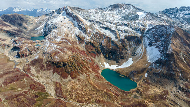 Aerial view of vibrant turquoise lakes nestled amid rugged, snow-dusted peaks and textured autumnal slopes, Neelum Valley, Azad Kashmir, Pakistan.