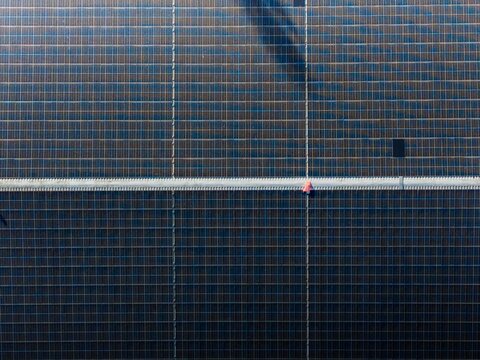 Aerial view of a symmetrical grid of solar panels, reflecting light under the sun, creating a stark geometric pattern, Exeter, England, United Kingdom.