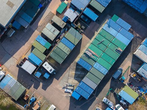 Aerial view of the landscape with rows of colorful shipping containers casting long shadows under the afternoon sun, Exeter, England, United Kingdom.