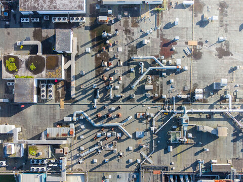 Aerial view of rooftops adorned with mechanical equipment and vegetation, contrasting against the gray urban sprawl, Exeter, England, United Kingdom.