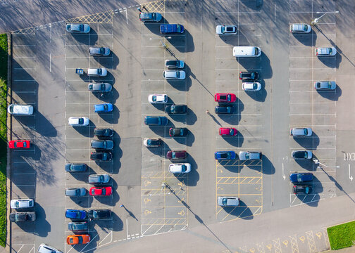 Aerial view of vibrant cars pop against the stark grey asphalt of the parking lot, framed by crisp white lines, Exeter, England, United Kingdom.