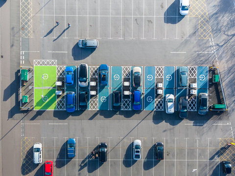 Aerial view of the car park with colorful electric charging bays casting long shadows on the asphalt, Exeter, England, United Kingdom.
