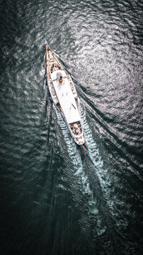 Aerial view of a boat sailing on the water, leaving a trail of ripples and patterns across the dark surface, Saint-Prex, Vaud, Switzerland.