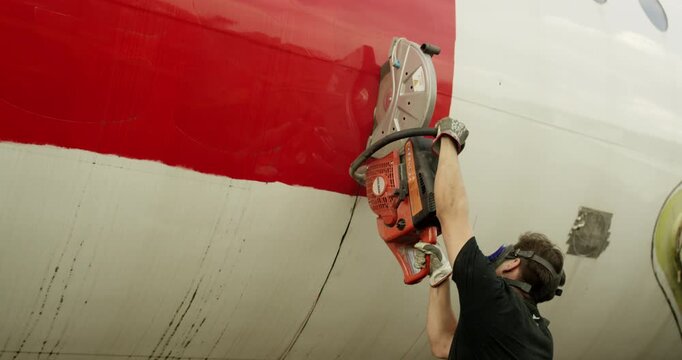 Close up of a man in safety gear using an angle grinder on the exterior of an aircraft body