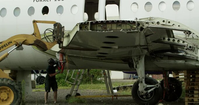 Close up of a technician using a grinding tool on a metal part of an aircraft fuselage outdoors