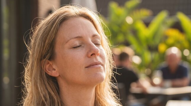 Mindfulness and inner peace concept, serene woman with eyes closed basking in warm sunlight. Mental health, wellness and relaxation for stress relief.