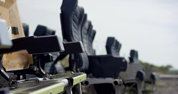 Close up side view of discarded passenger seats stored outdoors in an aircraft salvage facility