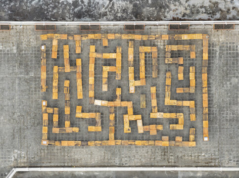 Aerial view of a playful maze created from old wooden student desks and chairs on a school rooftop with grey tiled flooring Taiwan.