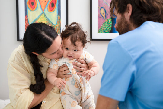 Doctor observing a heartwarming interaction between a mother and her child in a medical office