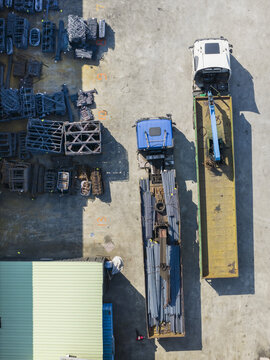 Aerial view of trucks loaded with metal rods and industrial equipment parked in an outdoor yard at an iron factory Taiwan.