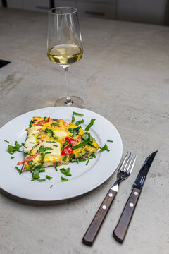 Cooking an italian frittata with mozarella, asparagus, eggs, onions, tomatoes and fresh herbs in spring time at home in the kitchen