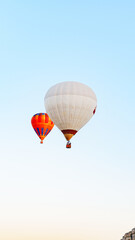 Obraz premium Hot air balloons rise into the clear sky over the countryside at dawn near a small town