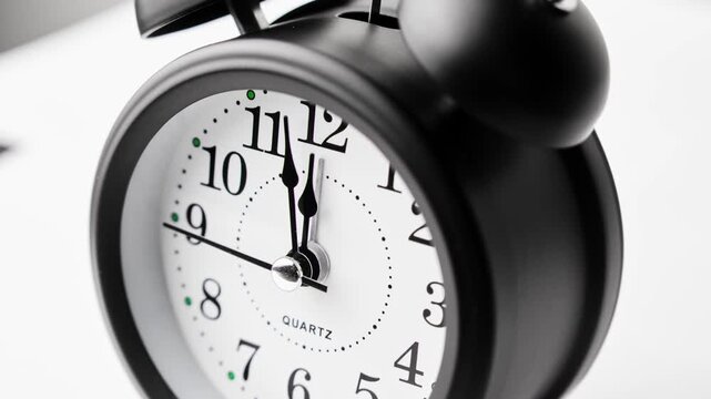 Striking black clock elegantly ticks in light setting, marking time. Time moving fast. Time concept. Table clock show running time. Close-up in 4K, UHD