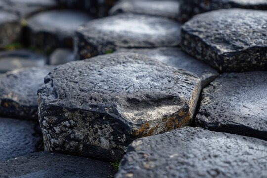 Close-up of hexagonal rock formations, textured with shades of gray and black, resembling a pavement