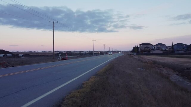 Car on a rural road approaching drone overhead shot evening overcast