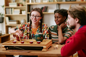 Fototapeta premium Young adult diverse friends preparing tea and sharing cultural ritual at table, demonstrating social connection and leisure