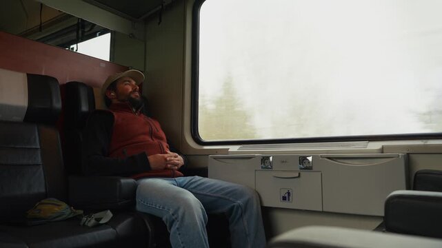 A Man Sits on a Train Seat With His Eyes Closed, Leaning Back and Resting Peacefully During the Journey - Medium Shot