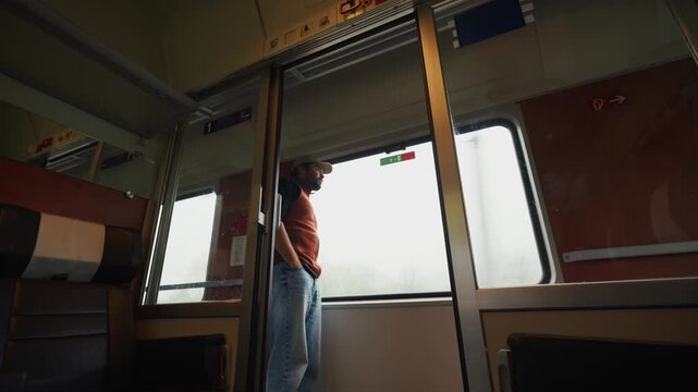 A Man Stands Pensively by the Train Window, Gazing at the Blurred Scenery Passing Outside - Medium Shot