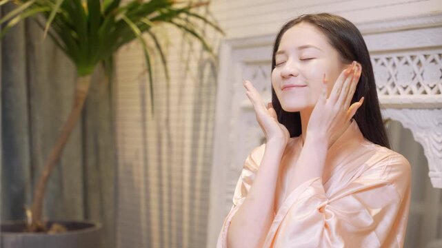 Smiling beauty girl doing her skincare routine, woman hands gently pressed patting or massaging moisturizing lotion or skin care white cream product onto face, home self-care spa procedures treatment