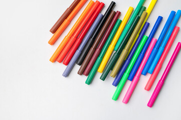 Fototapeta premium Brightly colored plastic markers on gray background top view. Felt-tip pens for arts and crafts, drawing, creative projects. School and preschool supplies. Background with markers, rainbow colors