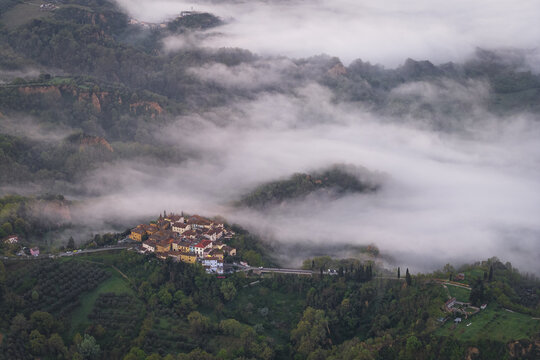 Aerial view of the village of Botriolo and Le Balze del Valdarno clay formations emerging from thick morning fog in the Tuscan hills Botriolo, Toscana, Italy.