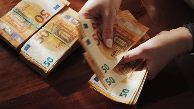 A woman counts a 50-euro note. Close-up of a hand counting a stack of bills. Salary and savings. High quality 4k footage