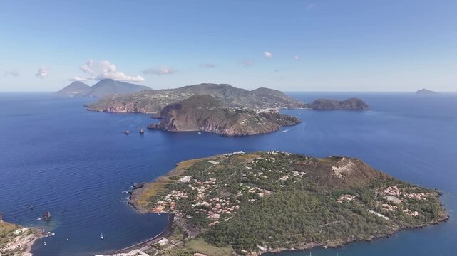 Aerial drone slowly flying forward from Vulcano crater towards Lipari island across Mediterranean sea.