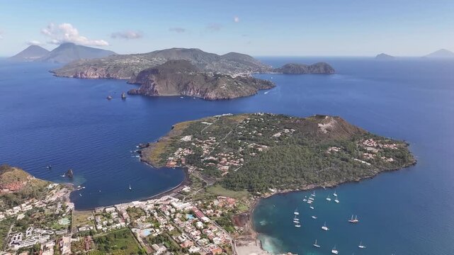 Drone flying in circular motion from volcanic crater on Vulcano island revealing Lipari island in the distance.