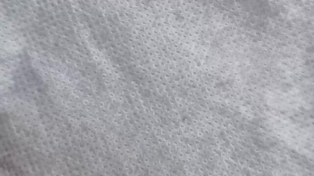Abstract faded white color style fabric sheet surface background texture with copy space. Stop motion animation loop. Closeup macro top view.