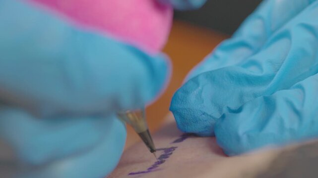 Professional tattoo artist working with precision, wearing blue gloves while tattooing client in studio - close-up footage