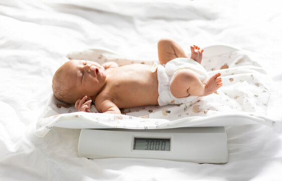 A newborn baby is weighed on a digital scale, showing a healthy birth weight