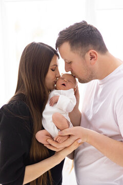 A loving mother and father gently kiss their newborn baby, celebrating the start of their family journey