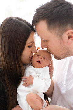 A mother and father tenderly embrace their newborn baby, sharing a moment of pure love and connection