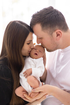 A tender moment captured as parents embrace their newborn baby, showcasing love and family connection in a soft, natural light