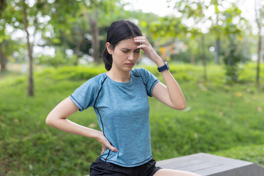 women feeling headache and lower back pain after outdoor workout in park. Fatigue, muscle strain, stress, health problem, fitness injury.